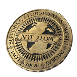 Angel Aberdeen – Human Being Coin in brass – back engraved with Not Alone, surrounded by people holding hands around the globe, additional words including Love, Suffering, Forgiveness, and I'm Okay