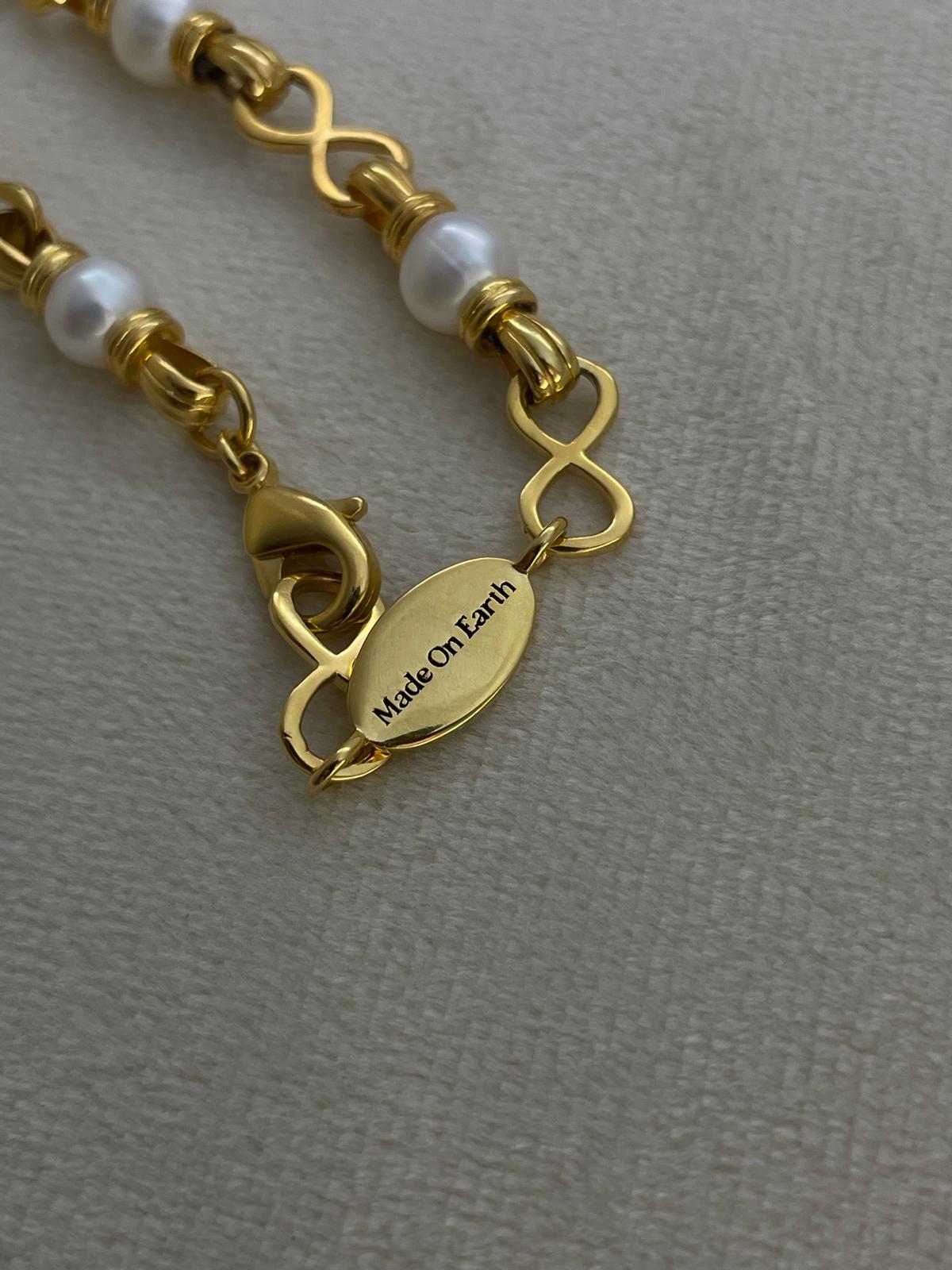 Angel Aberdeen – Forever Connected necklace – detail view showing brand tag with Made On Earth engraving in 18k PVD gold plating with enamel inlay and pearl accents