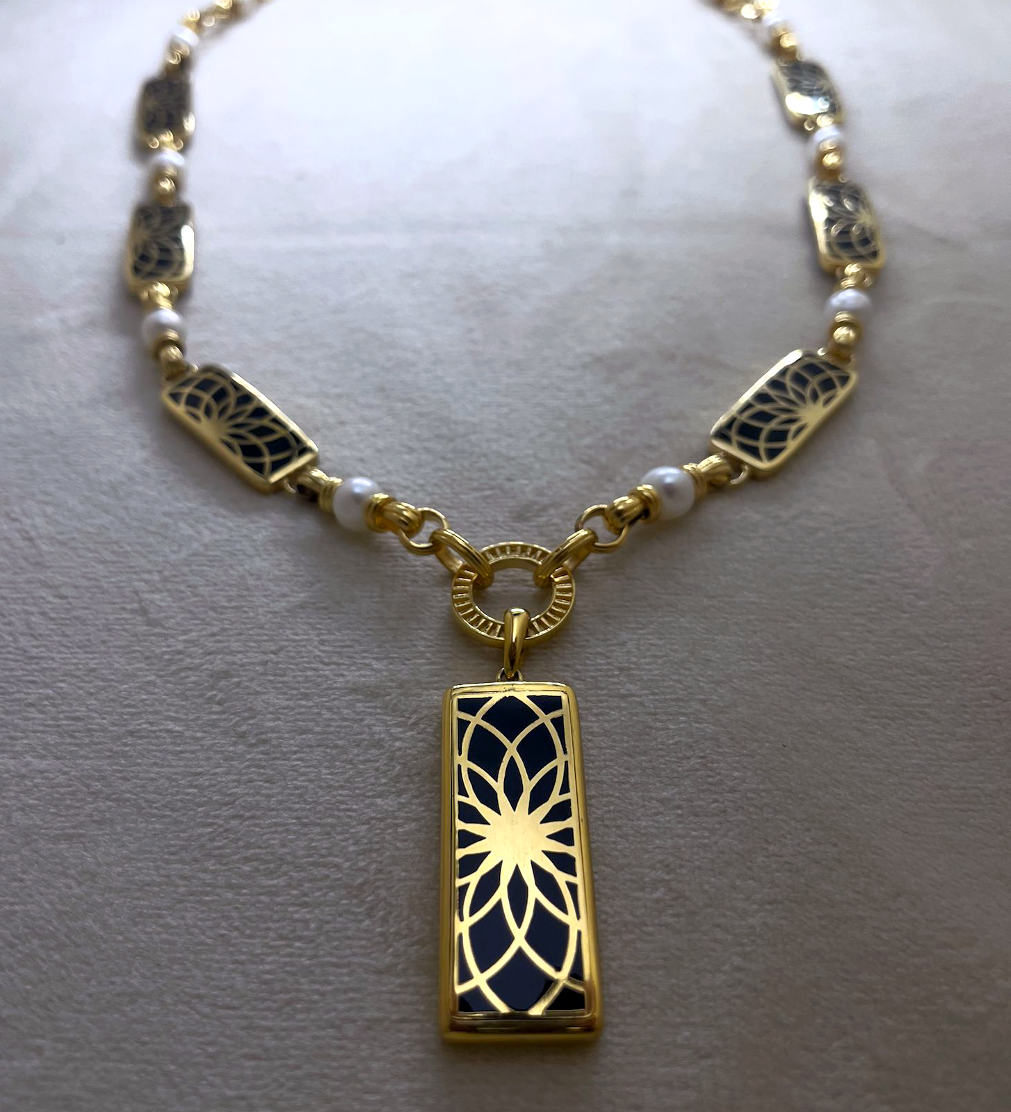 Angel Aberdeen – Forever Connected station necklace – 18k PVD gold plated with black enamel inlay and pearls – front view with sacred geometric torus pendant and linked design