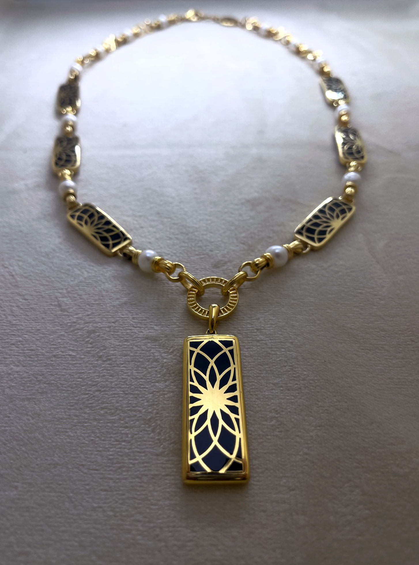 Angel Aberdeen – Forever Connected station necklace – 18k PVD gold plated with black enamel inlay and pearls – front view with sacred geometric torus pendant and linked design