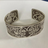Front image Hand-engraved sterling silver cuff.  Floral Montana rose engraving covers the entire front.  A one-of-a-kind bracelet celebrating strength, healing, and rebirth.