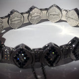 Close-up of engraved 14-karat white gold bracelet links with words like Laughter, Cultivate Love, Heart Smile, and Compassion on a royal blue background.